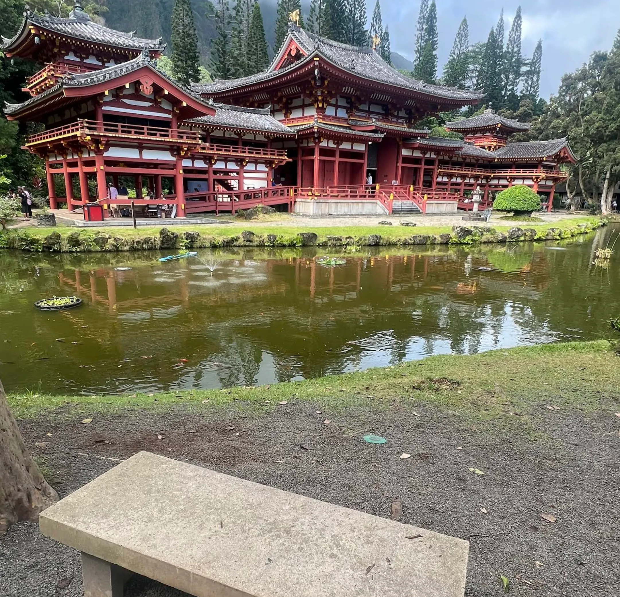 Image: Family ringing the peace bell at Byodo-In Temple with koi pond and green peaks behind