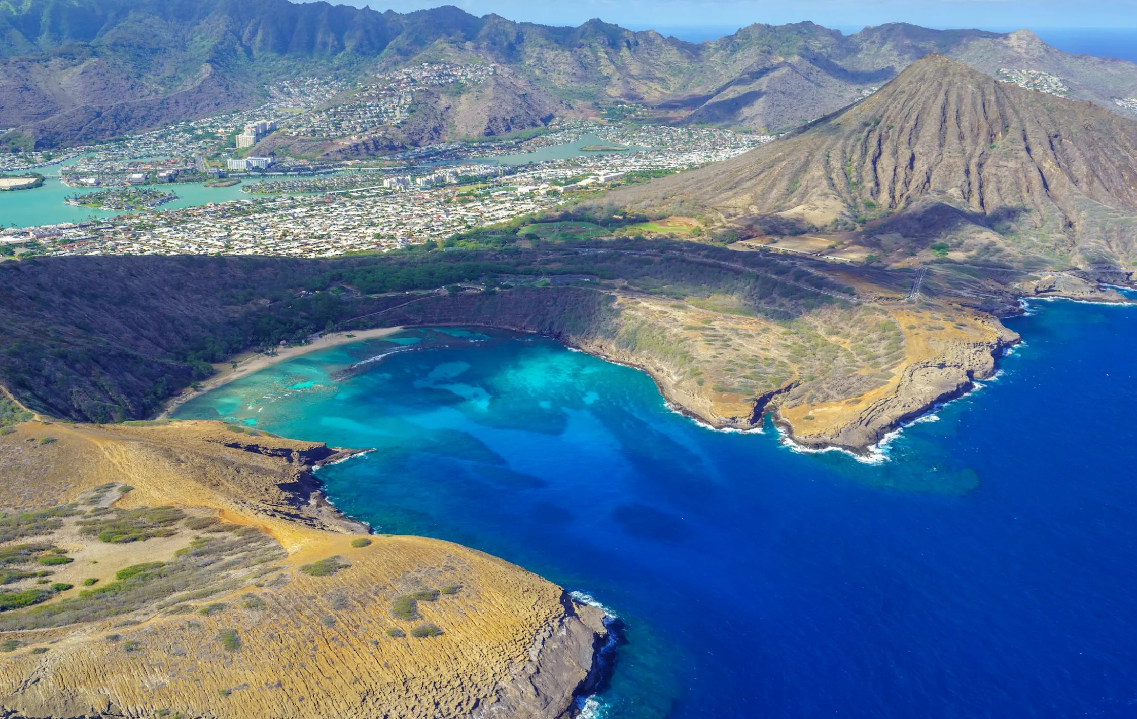 Image: Parent and child floating over coral at Hanauma Bay, with a lifeguard stand in the distance