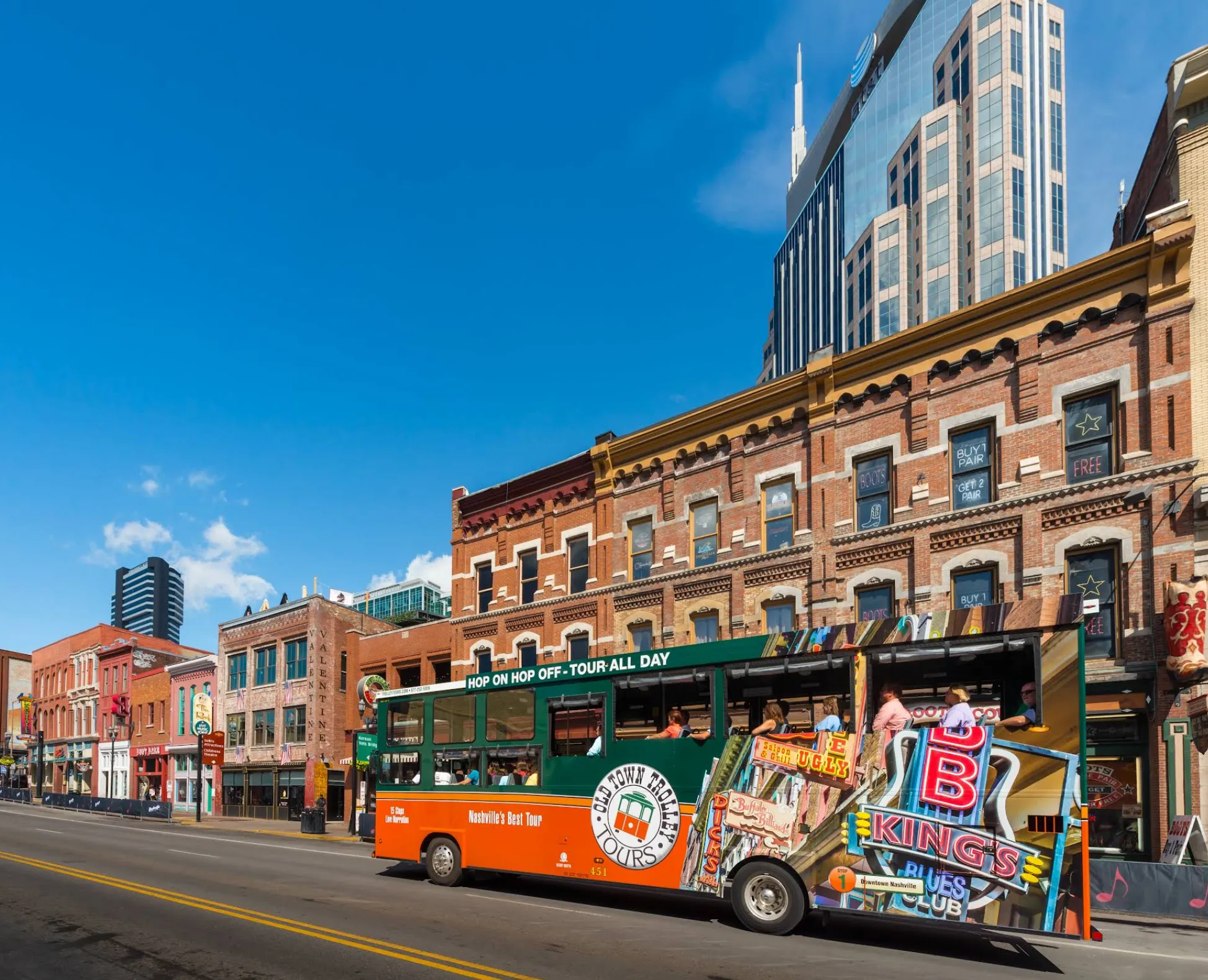 Image: Family boarding a red hop-on hop-off trolley in downtown Nashville